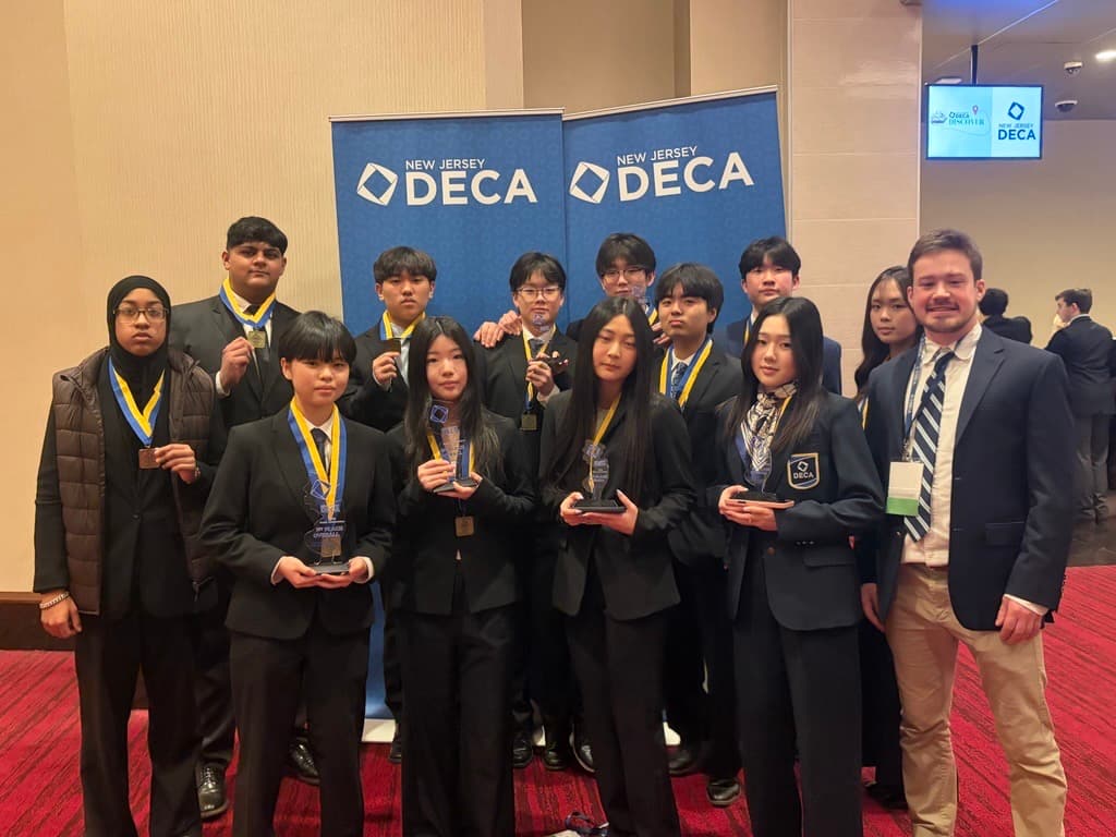 DMAE DECA students and their advisor holding medals and awards at a New Jersey DECA competition